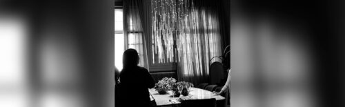 Foto de uma mulher sentada em uma mesa em frente a um lustre