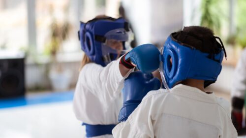Girl and boy having fight while wearing protective gloves and helmets